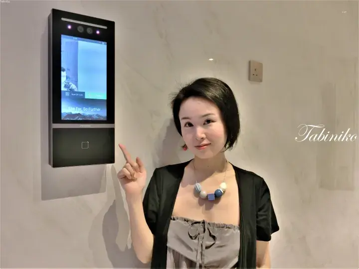 Woman pointing to a Hikvision smart access control panel with QR code scanning and facial recognition features.