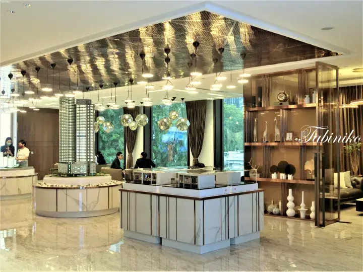 Luxury real estate showroom featuring architectural models, marble counters, and elegant pendant lighting.