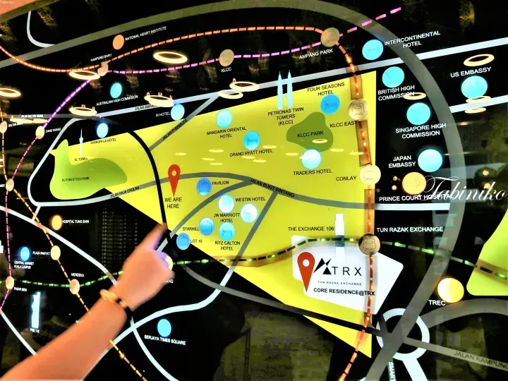 Hand pointing at a glowing TRX Core Residence location map showing nearby landmarks like KLCC and Pavilion in Kuala Lumpur.
