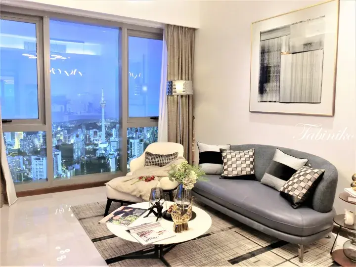 Modern living room with grey sofa and KL Tower view from high-rise apartment window.