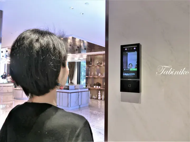 Woman using a Hikvision smart access control system at a modern property showroom entrance.
