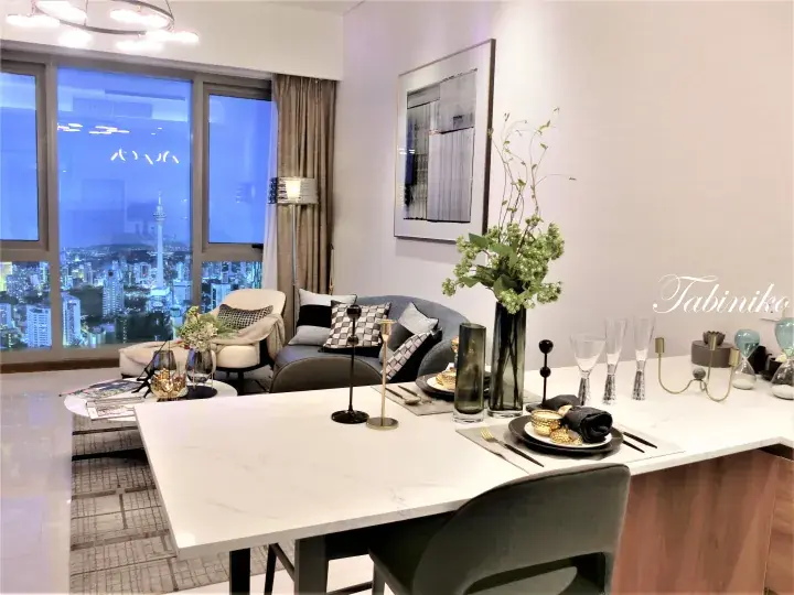 Modern dining area with marble table overlooking Kuala Lumpur skyline and KL Tower at night.