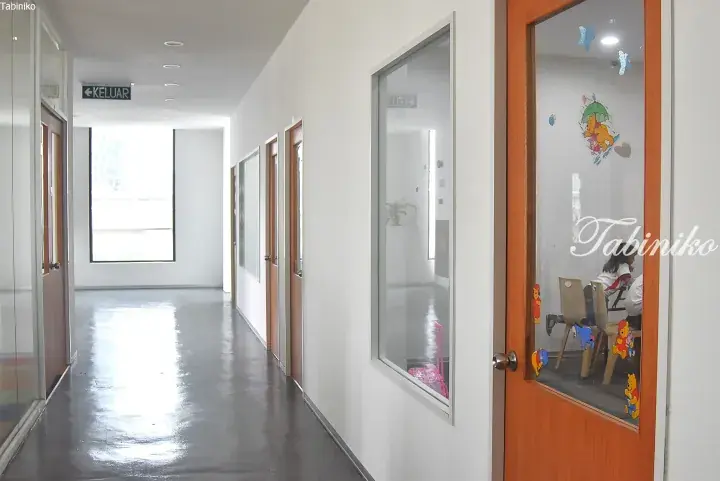Bright hallway with polished floors, wooden doors, and glass panels showing a child’s playroom with Winnie the Pooh stickers.