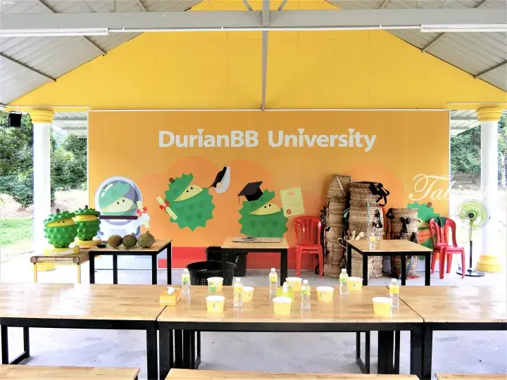 DurianBB University event space with yellow wall, durian mascot, tables, and woven baskets.