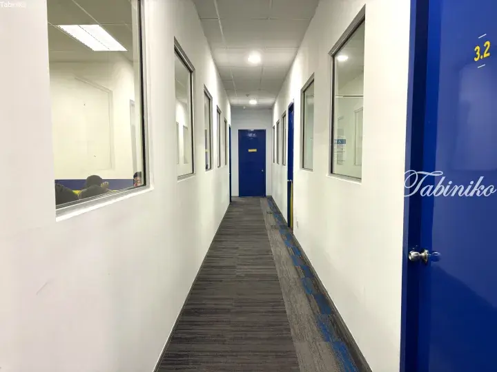 Bright hallway with blue doors and glass windows leading to a study room in a modern educational facility.