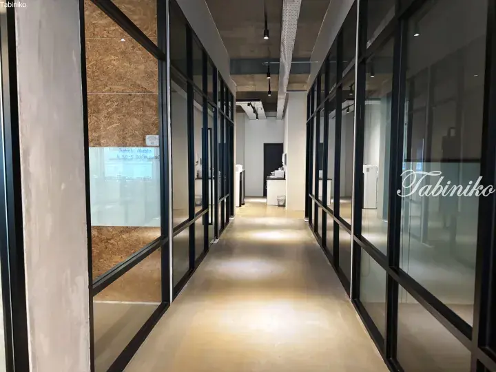 Modern office hallway with glass-walled meeting rooms and polished concrete floors.