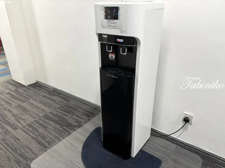 A white and black Natural Water dispenser with hot and cold options in a modern office space.