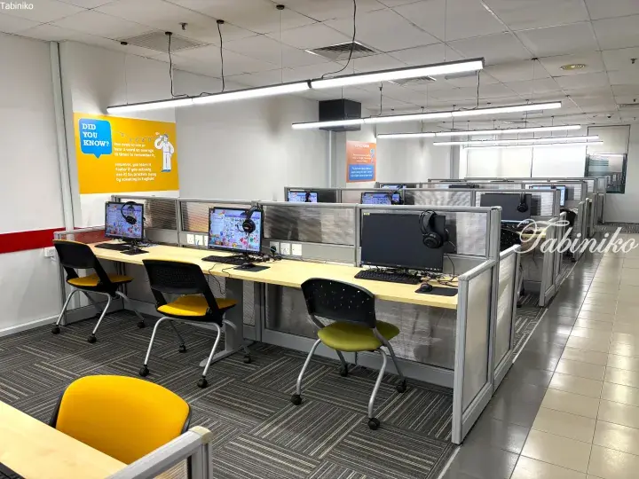 Modern language center computer lab with rows of workstations, monitors, and yellow chairs in a bright open-plan room.