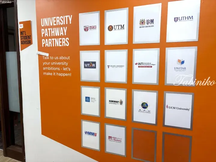 Orange wall displaying University Pathway Partners logos including UPM, UTM, USM, and Taylor’s University for international student advising.