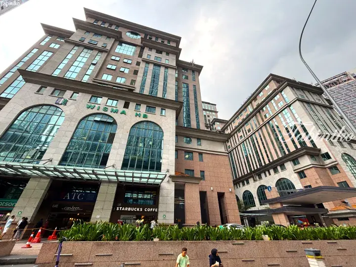 Wisma HB building facade in Kuala Lumpur featuring large arched windows, Starbucks, and ATC Advance Tertiary College entrance.
