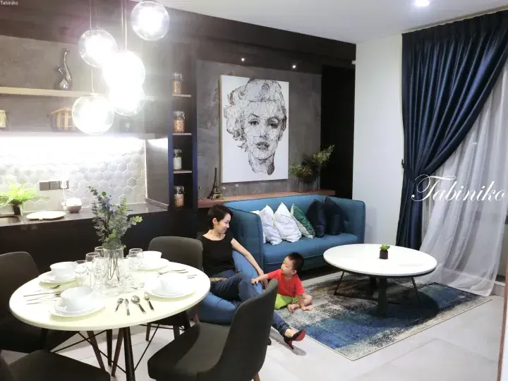 Woman and child relaxing in a modern apartment living room with blue sofa and geometric wall art.