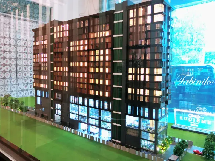 Architectural model of Embrique Kuala Lumpur condo showing illuminated windows and green surroundings.