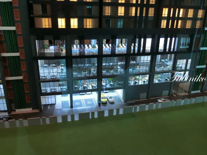 Architectural model of a modern hotel featuring a multi-story atrium with a pool, dining areas, and ground-floor parking.