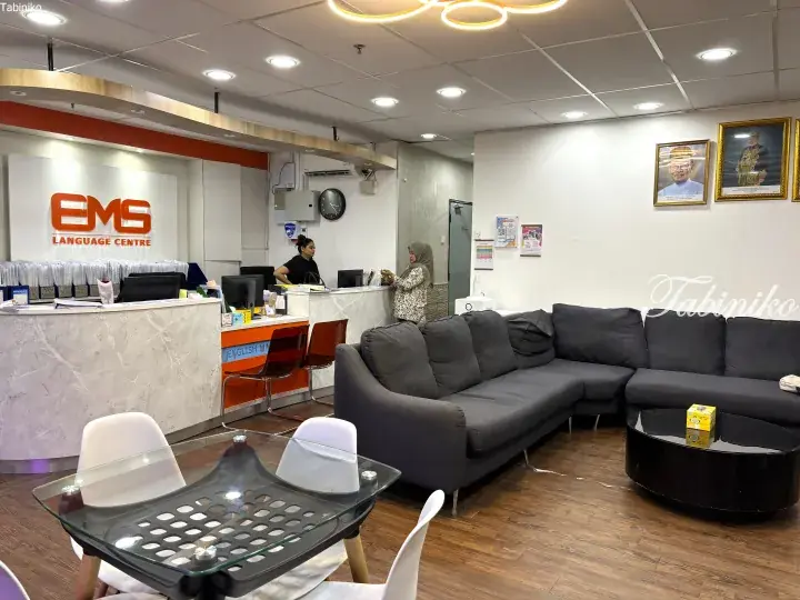 Reception area of EMS Language Centre with marble counter, grey sofa, and portraits on the wall.