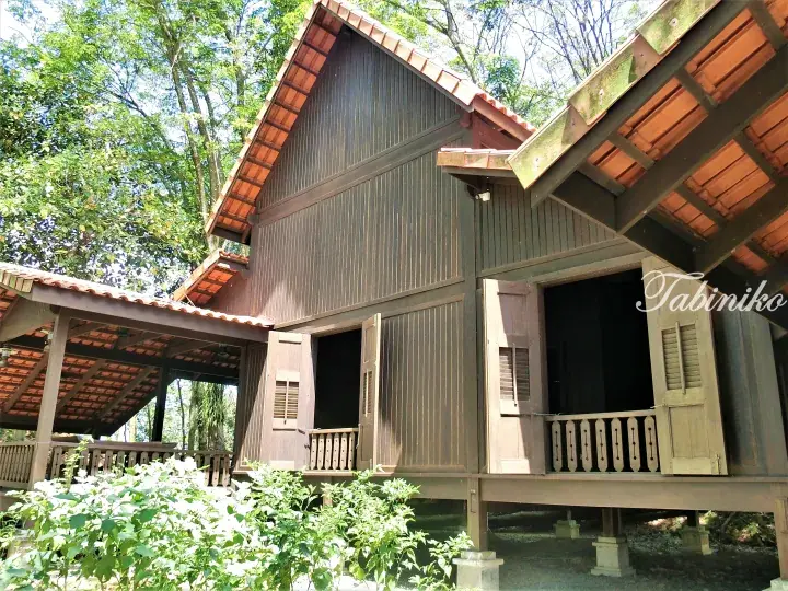 Traditional wooden bungalow with veranda and tiled roof in lush greenery