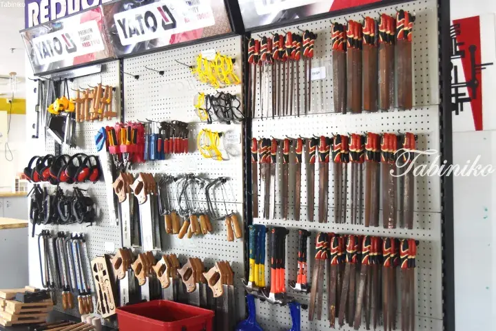 Wall-mounted pegboard displaying organized woodworking tools including saws, files, clamps, and safety gear.
