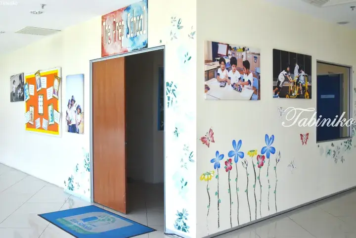 Bright hallway of The Prep School with children’s photos, flower wall decals, and a welcome mat.