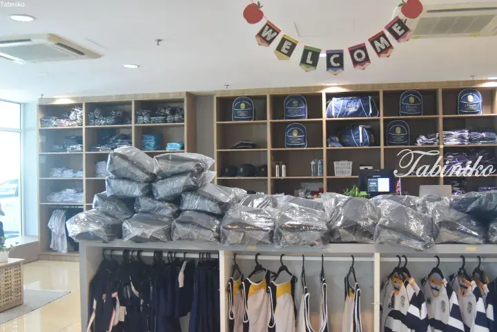 Epsom College merchandise shop displaying school bags, uniforms, and sports jerseys on shelves and racks.