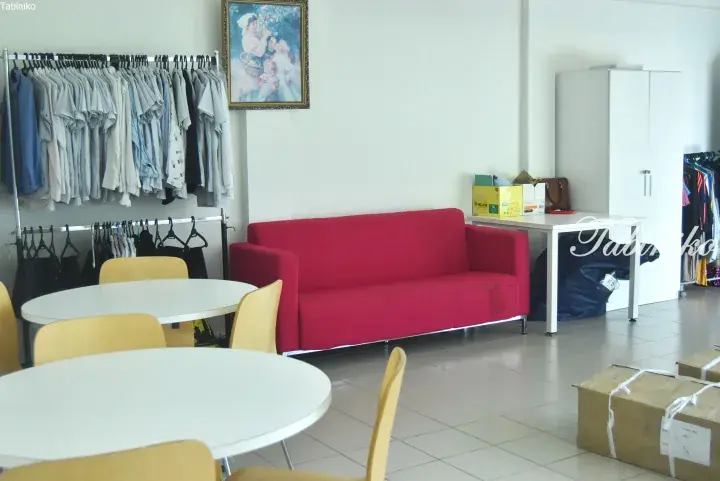 Bright room with red sofa, clothing racks, and round tables in a Malaysian property or boutique space.