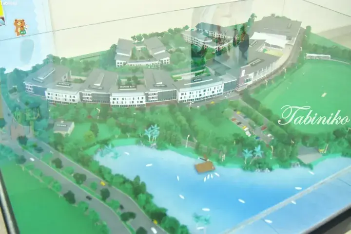 Architectural model of a modern campus with science, library, and sports facilities beside a lake.