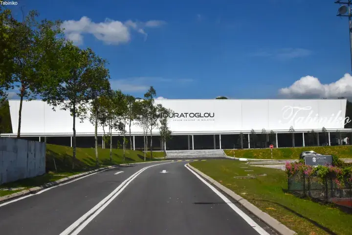 Modern white building of Epsom College in Malaysia with Mouratoglou branding, set against a blue sky.