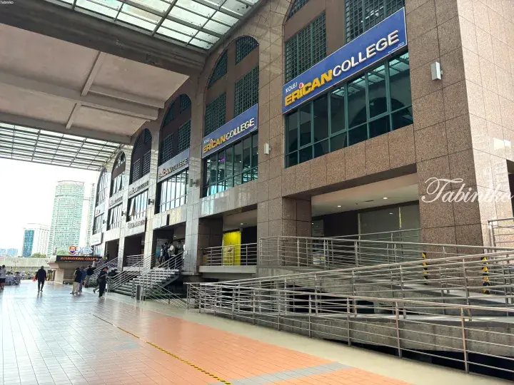 Exterior view of Kolej Erian College building with multiple signs, stairs, and walkway in an urban setting.