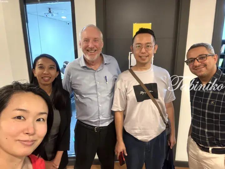 Group of five diverse travelers and locals smiling together in a modern office setting.