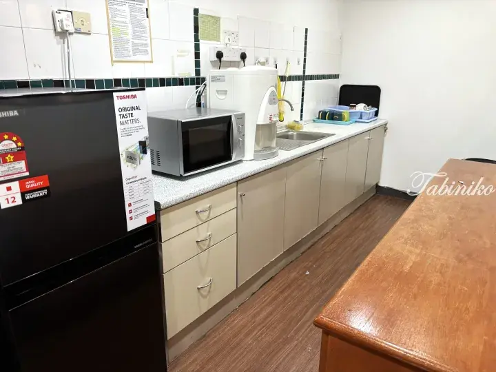 Kitchenette with a Toshiba refrigerator, microwave, water dispenser, and sink in a Malaysia rental property.