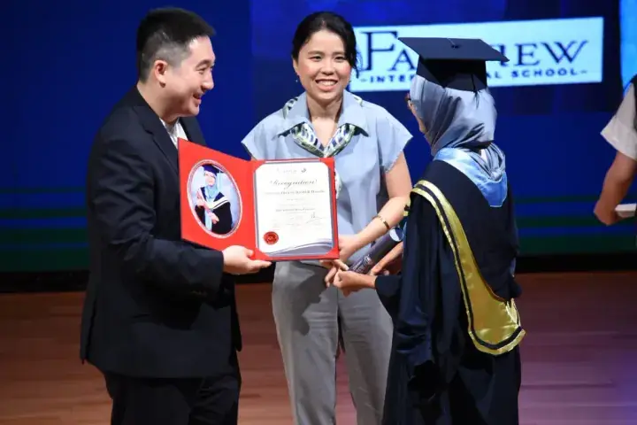 Graduation ceremony at Fairview International School with a student receiving a certificate.