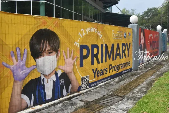 Fairview International School banner advertising Primary Years Programme for ages 3-12 with a child showing painted hands.