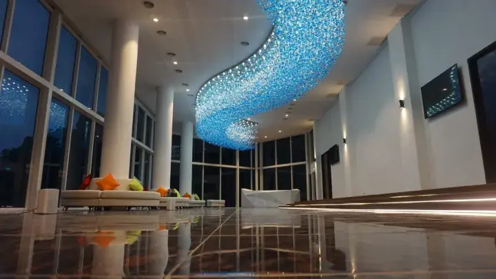 Modern hotel lobby with a large blue crystal chandelier and floor-to-ceiling windows.