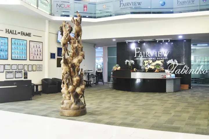 Lobby of Fairview International School featuring a large horse sculpture, reception desk, and Hall of Fame display.