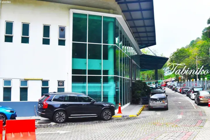 Black Volvo SUV parked outside a modern white building with large glass windows in Malaysia.