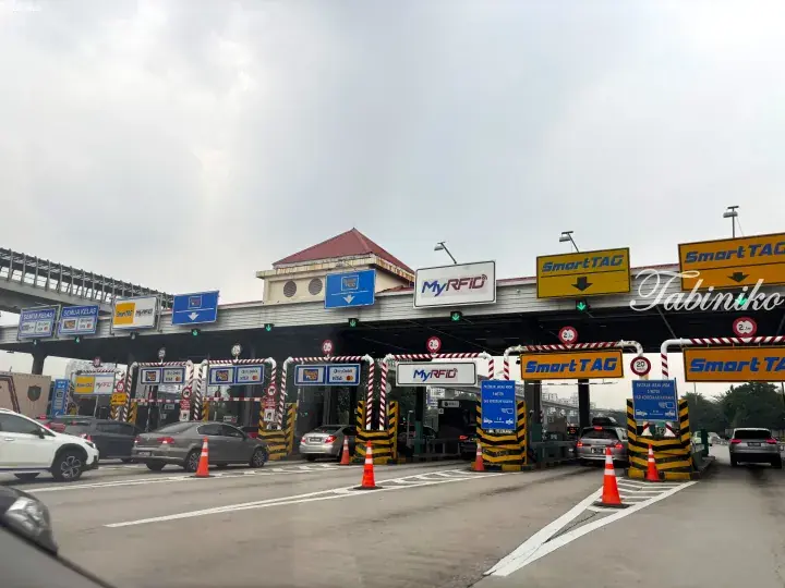 Cars passing through a Malaysian highway toll plaza with SmartTAG and Touch &rsquo;n Go lanes.