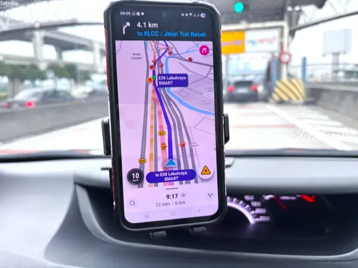 Car dashboard view showing smartphone navigation to KLCC via SMART highway in Kuala Lumpur.