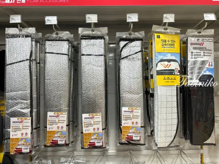 Shelves of packaged car sunshades with reflective surfaces and price tags in a Malaysian store.