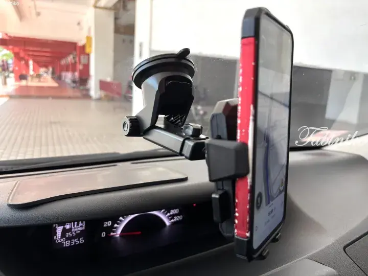 Car dashboard with smartphone mounted on windshield displaying navigation map for Malaysia road trip