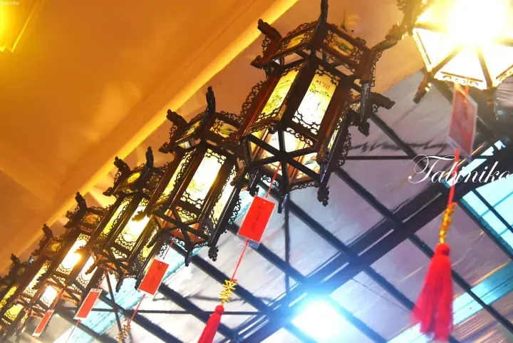 Ornate wooden Chinese lanterns with red tassels hanging from a ceiling.