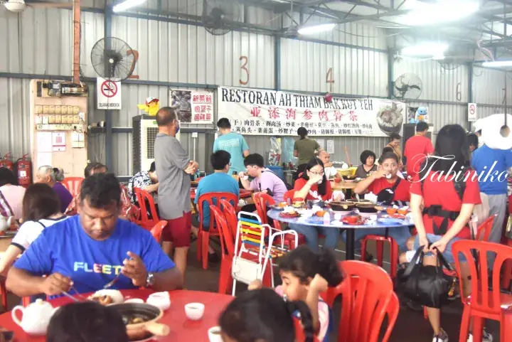 Diners enjoying Bak Kut Teh at the bustling Ah Thiam Bak Kut Teh restaurant in Malaysia.