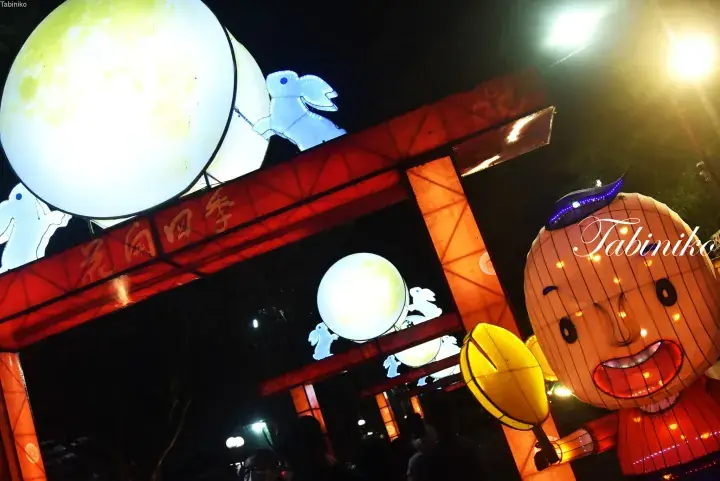 Illuminated lanterns featuring a large moon and rabbit at a night festival entrance in Malaysia.