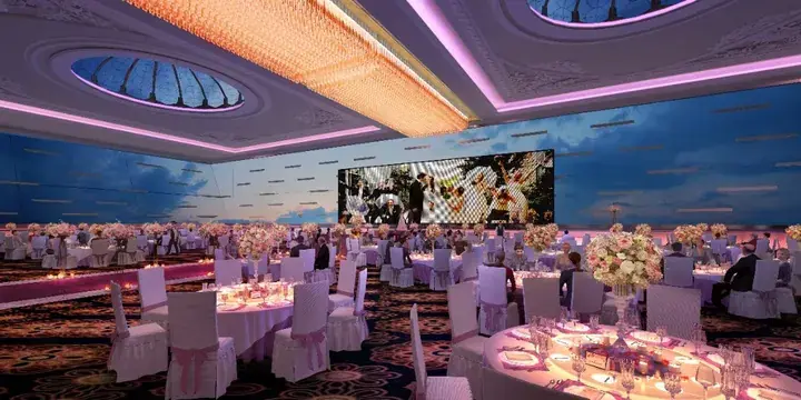 Luxurious wedding banquet hall with round tables, floral centerpieces, and a large LED screen displaying a couple.