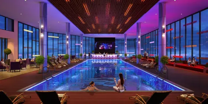 Luxury indoor infinity pool with blue lighting, lounge chairs, and a stage at a high-end resort.