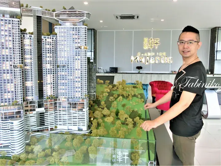A man stands beside the Grand Ion Majestic architectural model in the sales gallery.