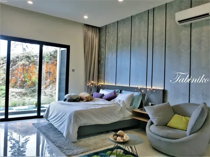 Modern bedroom with a king bed, grey accent wall, and large window overlooking a hillside.