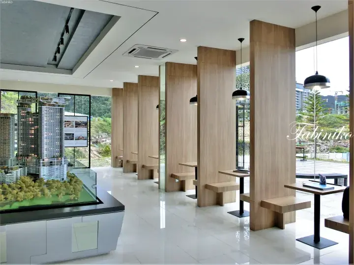 Modern property showroom with wooden seating booths, black pendant lights, and a detailed architectural model.