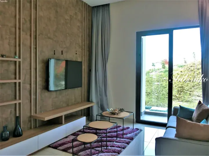 Modern living room with wooden wall paneling, flat-screen TV, purple rug, and glass door opening to a green garden view.
