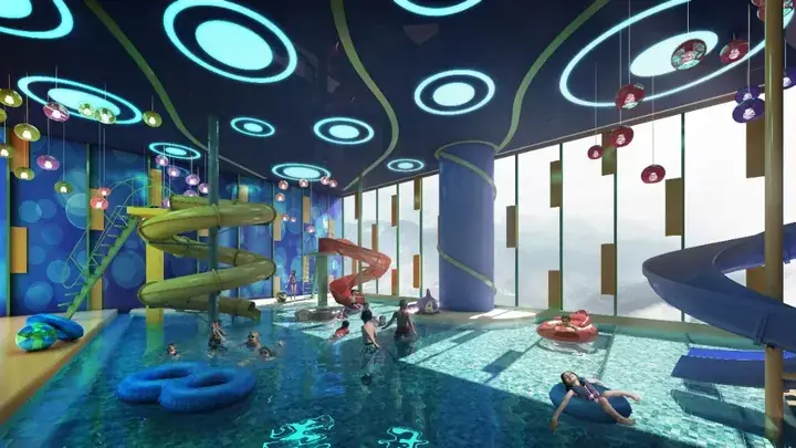 Colorful indoor water park with slides and circular ceiling lights, featuring families enjoying the pool.