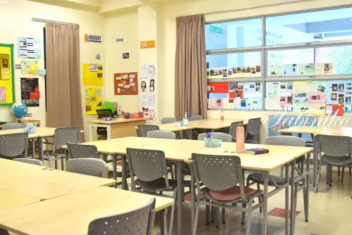 Bright classroom with student artwork, globe, and group tables at an international school in Malaysia.