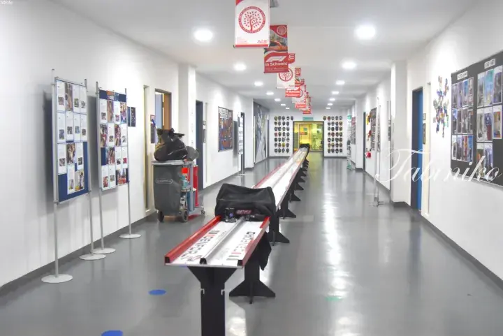 Long hallway with F1 in Schools racing tracks and student artwork displays at a Malaysian school.