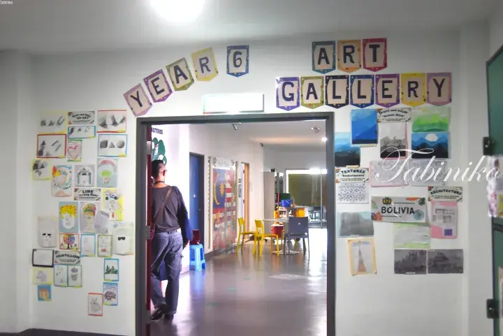 Year 6 Art Gallery entrance with student artwork displayed on the walls and a visitor walking inside.
